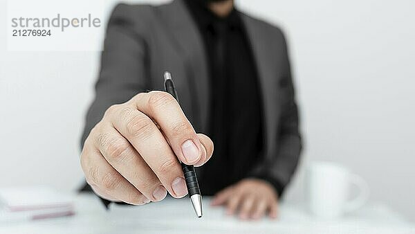 Männliche Person sitzt am Tisch und zeigt mit einem Stift auf eine wichtige Nachricht