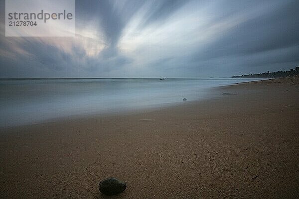 Landschaft am Meer. Langer einsamer Strand mit Blick auf das Wasser bis zum Horizont. Die Wellen eines Sturms brechen sich im Sand und verleihen dem Bild bei Sonnenuntergang eine besondere Note. Bentota  Sri Lanka  Asien