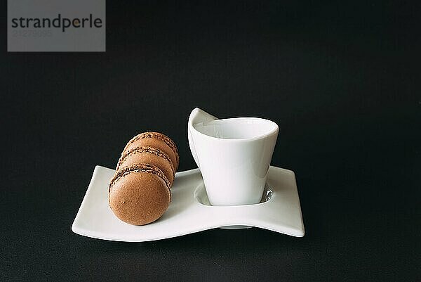 Set von Tasse Kaffee und Macarons vor schwarzem Hintergrund. Selektiver Fokus