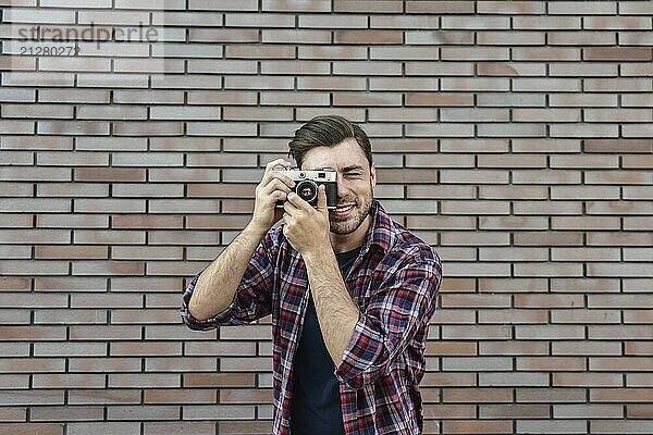 Mann mit Retro Fotokamera Mode Reisen Lifestyle im Freien  während stehend gegen Backsteinmauer Hintergrund