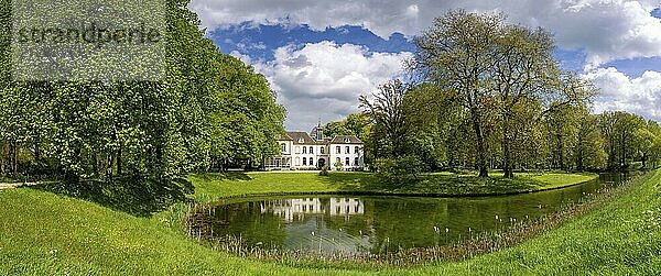 Blick auf das Herrenhaus te Baak  das sich in seinem Wassergraben spiegelt und von schönen Bäumen mit frischen grünen Blättern umgeben ist