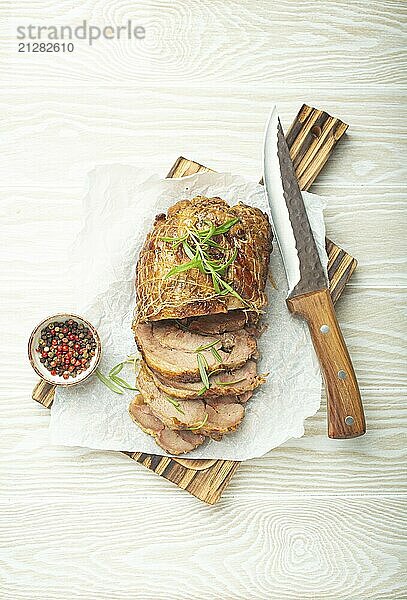 Rolled Truthahn gebraten mit Gewürzen und Kräutern auf Backpapier mit Messer und Holz weißen Hintergrund Draufsicht. Gebackene Schnitt für Scheiben Putenfilet Rolle zum Abendessen  Lebensmittel Fotografie