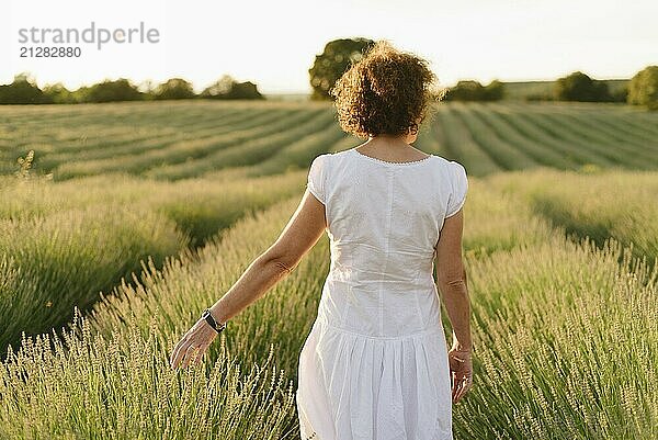 Schöne Frau in einem weißen Kleid geht im Lavendelfeld