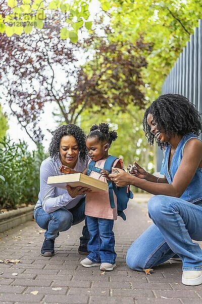 Vertikales Porträt einer afrikanischen Frau der dritten Generation in der Stadt  die es genießt  ein Mädchen von der Schule abzuholen