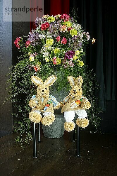 2 Osterhasen sitzen vor einem schönen Blumenschmuck