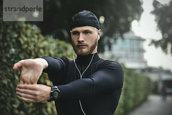 Muskulöser Sportler beim Dehnen vor einem Sporttraining auf der Straße im Stadtpark