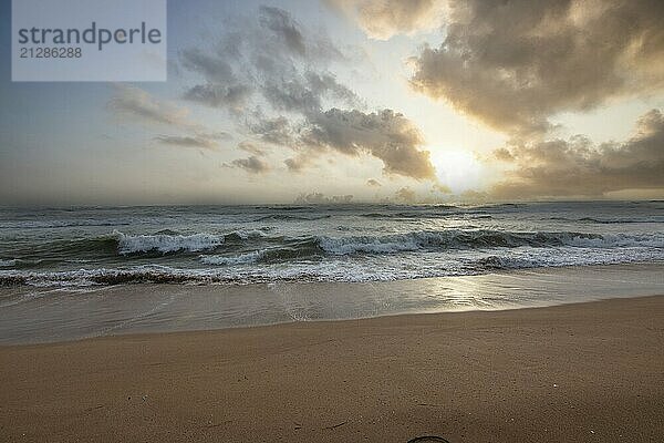 Landschaft am Meer. Langer einsamer Strand mit Blick auf das Wasser bis zum Horizont. Die Wellen eines Sturms brechen sich im Sand und verleihen dem Bild bei Sonnenuntergang eine besondere Note. Bentota  Sri Lanka  Asien