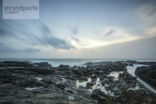 Strand  mit Lavafelsen und Vegetation  Blick auf das Meer am Abend bei Sonnenuntergang. Landschaft mit Wolken in Induruwa  Bentota Beach  Sri Lanka  Indien  Asien