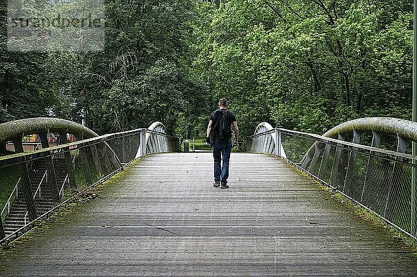 Mann geht über eine Fußgängerbrücke in Peterbos  Anderlecht  Region Brüssel Hauptstadt  Belgien. Modell freigegeben  inszenierte Situation