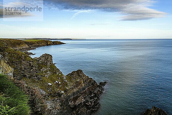 Landschaftlicher Blick auf die Klippen von Old Head auf der Halbinsel Kinsale in Irland mit grünen Hügeln bei Sonnenuntergang