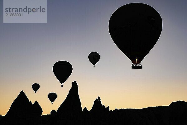 Silhouette von fliegenden Heißluftballons und Felslandschaft bei Sonnenaufgang in Goreme  Kappadokien  Türkei  Asien