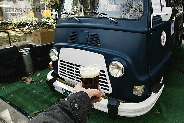 Mann mit einem Glas Bier vor einer alten Lebensmittelschiene. Fokus auf Bier