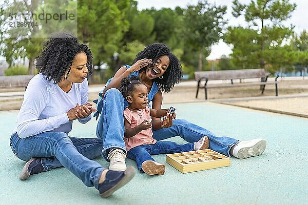 Weibliche afrikanische Mehrgenerationen Frau sitzt im Park mit Spielzeug für das Baby