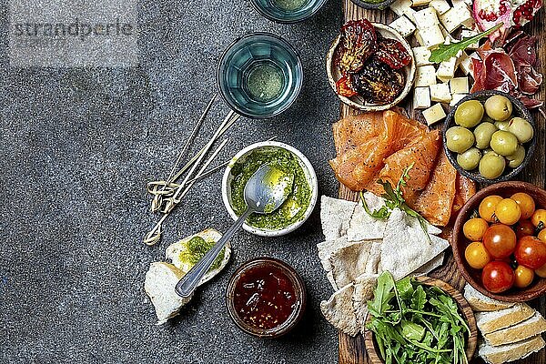 Antipasto. Wein Set Vorspeise. Schinken Serrano  geräucherter Lachs  getrocknete und frische Tomaten  Olivenkäse  Wein an Bord. Ansicht von oben  grauer Hintergrund aus Beton