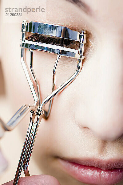 Extreme close up of a woman using an eyelash curler