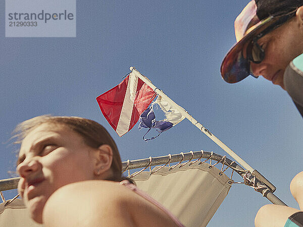 Low angle view father and daughter boating below diving flag