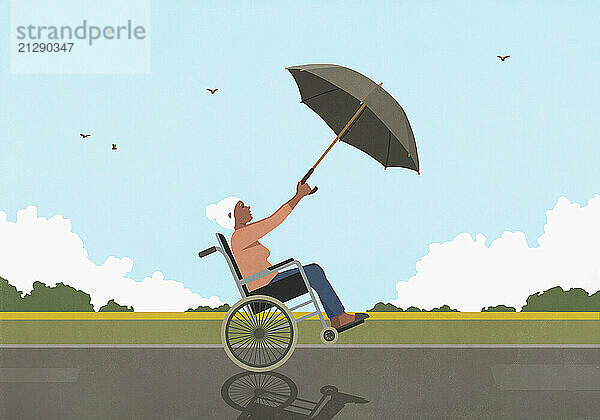 Senior woman in wheelchair using umbrella as sail in windy countryside