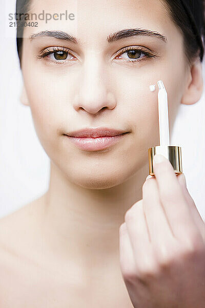 Close up of a young woman applying an anti-aging serum on her face with a dropper