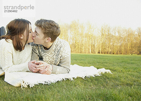 Young Couple lying on Grass Kissing