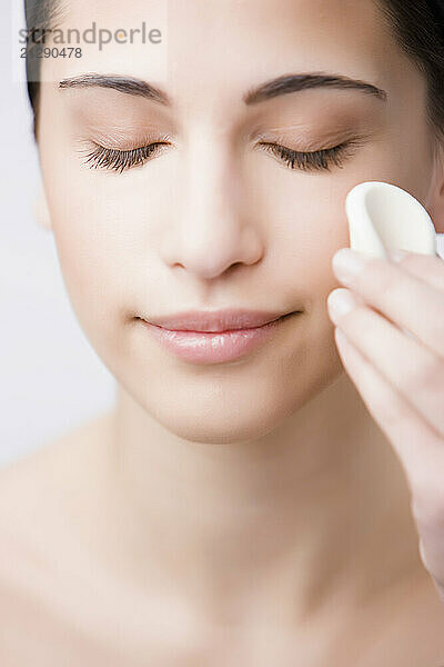 Close up of a young woman removing make up with sponge