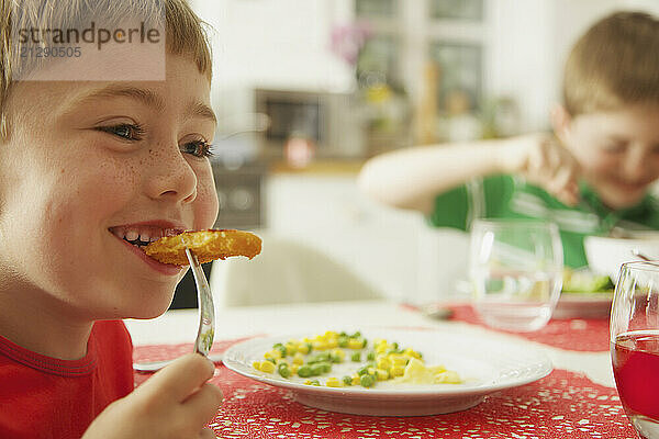 Young Boy Eating Fish fingers and Vegetables