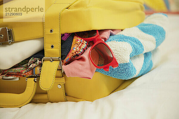 Yellow Suitcase Bursting with Clothing