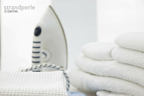 Close up of an iron and a stack of white towels