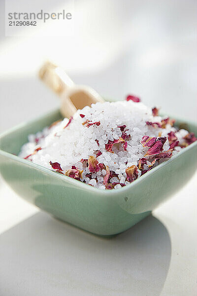 Close up of a ceramic bowl filled with bath salts and petals