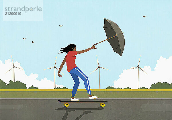 Woman with umbrella skateboarding in wind along rural wind turbines