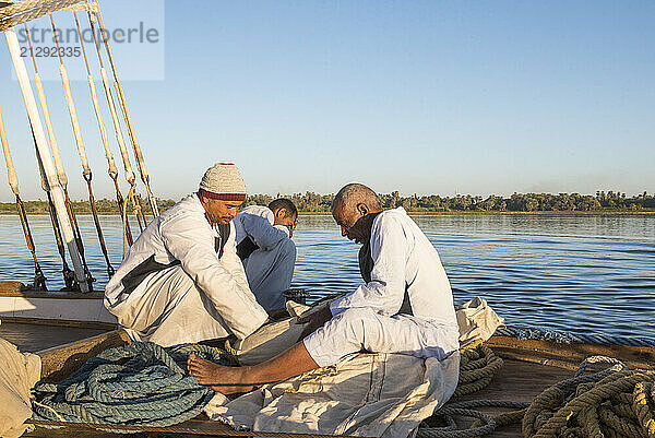 Members of the crew sitting at the prow of a dahabeah  passenger river boat of the Lazuli fleet  sailing on the Nile river  Egypt  North Africa  Africa