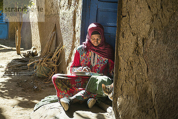 Woman sitting on her doorstep peeling garlic  village of Ramadi  west bank of the Nile south of Edfu  Egypt  North Africa  Africa