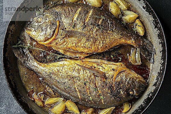 Food  Food  Baked sea bream or dorada with onion and herbs in pan on dark background