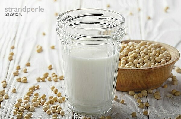 Non-dairy alternative Soy milk or yogurt in mason jar on white wooden table with soybeans in bowl aside