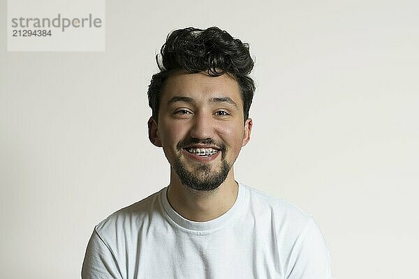 Portrait of a young man with braces smiling and laughing. A happy young man with braces on a white background