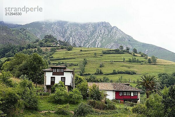 Scenic view of valley in Asturias with traditional farm buildings and green meadows a foggy day. La Goleta  Pilona  Spain  Europe