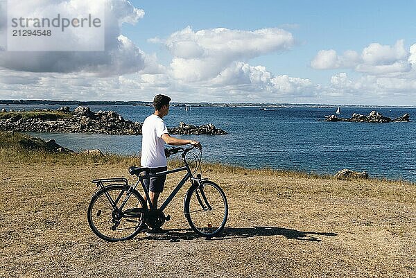 Attractive young male rides bicycle enjoying the views of landscape in the Island of Batz