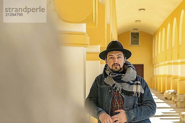 Portrait of a stylish handsome young man with a scarf outdoors. A serious man wearing a scarf  hat and a jaket looking confident at the camera