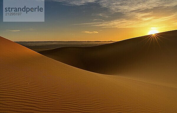 A view of the sand dunes at Erg Chebbi in Morocco at sunset with a sunstar