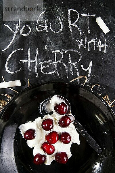 Presentation of desserts made with yogurt and cherries on a black background