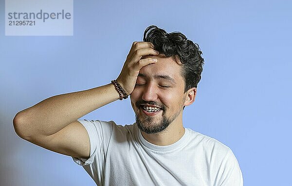 Portrait of a young man with braces smiling. A happy young man with braces on a blue background