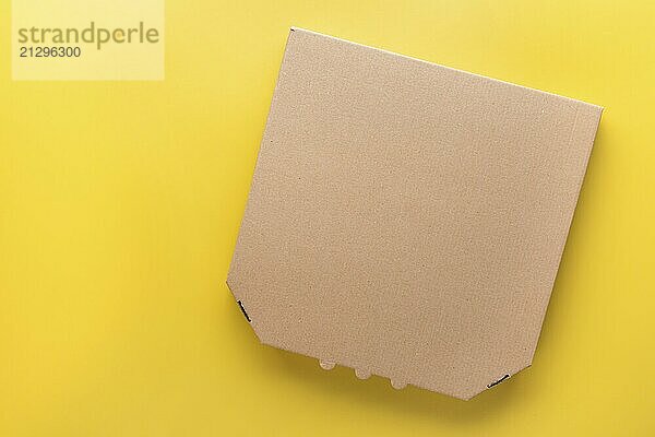 Pizza closed carton box on uniform yellow background flat lay mockup with blank space