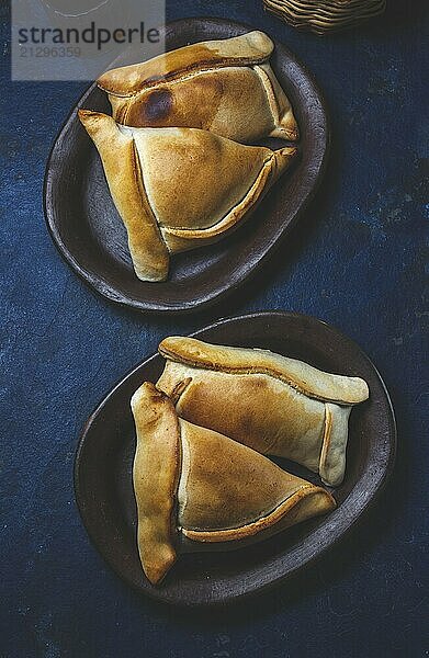 Food  Food  Tipical Chilean baked empanadas de pino y napolitano on clay plates with wine. Dish and drink on 18 September party Independence day Chile  blue background