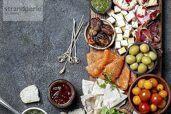 Food  Food  Antipasto. Wine set appetizer. Ham serrano  smoked salmon  dried and fresh tomatoes olive cheese  wine on board. Top view  gray cncrete background