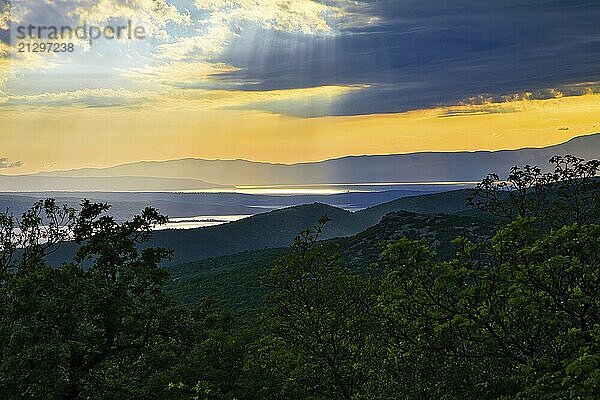 Natural view of the coast of Croatia surrounded by green mountains with sun rays breaking through the cloudy sky  Dalmatia  Croatia  Europe