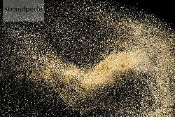 Dry river sand with stone explosion. Yellow colored sand splash against dark background