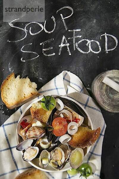 Presentation of a soup with seafood on a black background with writing