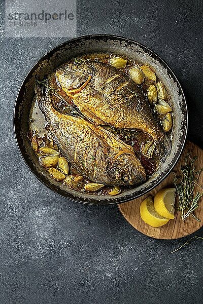 Food  Baked sea bream or dorada with onion and herbs in pan on dark background