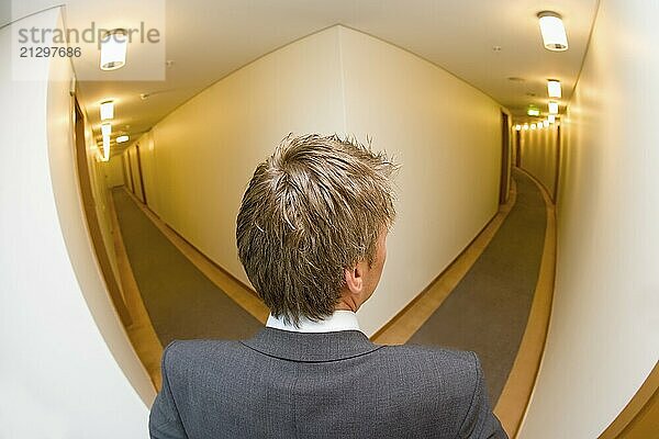 A businessman looking down the corridoor of a hotel shot from above