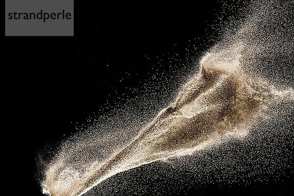 Dry river sand explosion. Golden colored sand splash against dark background