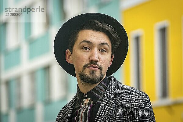 Portrait of a stylish handsome young man with a coat outdoors. A serious man wearing a coat  hat and a shirt looking confident at the camera